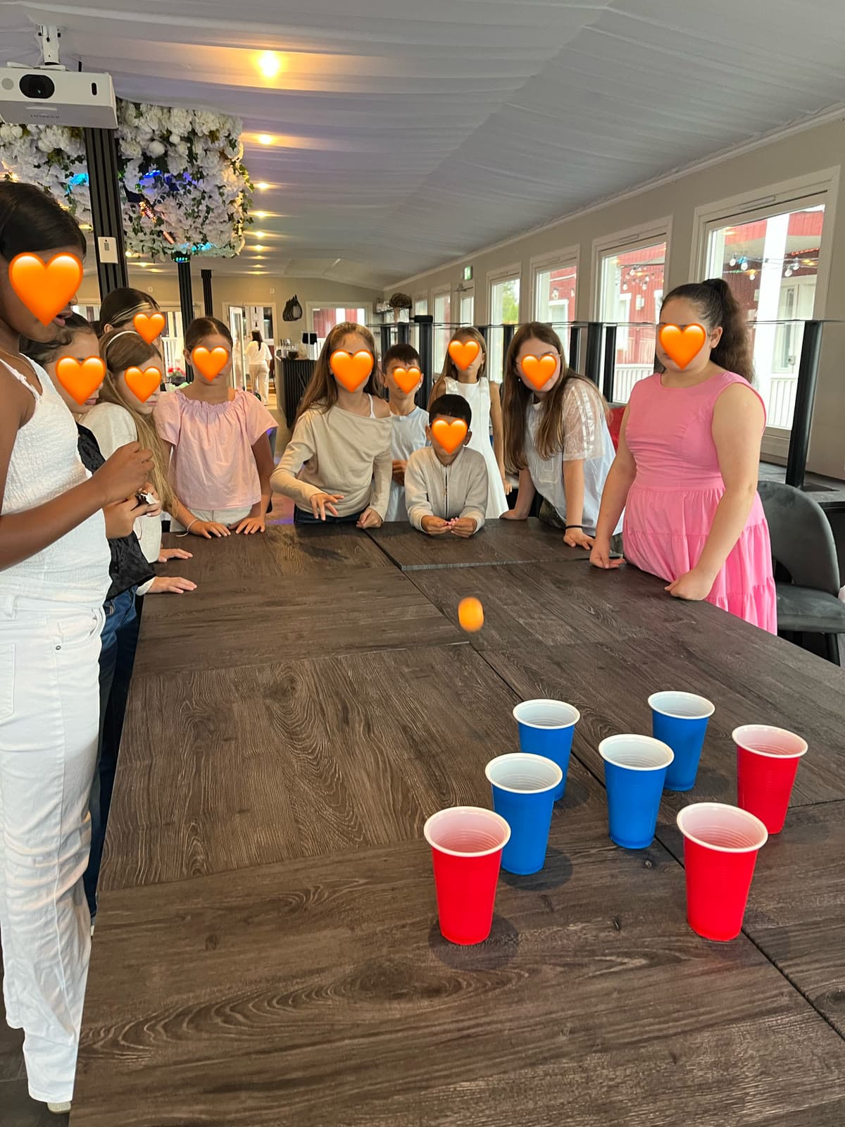 Barn som spelar bollspel med muggar tillsammans med lekledare på kalaset